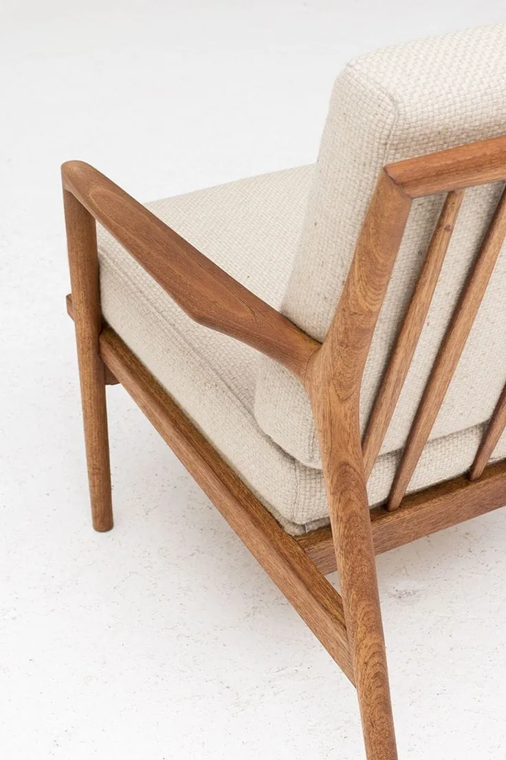 Detalle de una silla en madera con cojines tapizados en tela beige